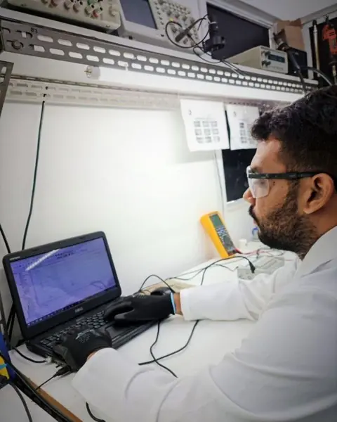 Técnico analisando um equipamento no computador do laboratório