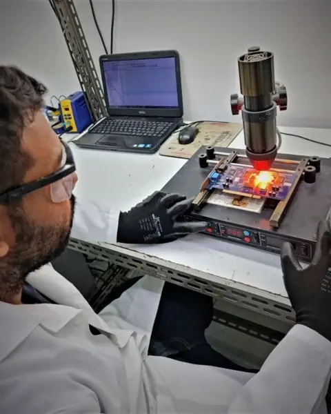 Técnico fazendo retrabalho de componentes em placa eletrônica